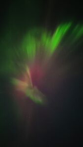 Aurora con raggi che sembrano diramarsi dal centro, verdi e rossi